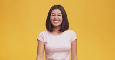 Kaygısız Asyalı kadın rock 'n roll el hareketi yapıyor, punk işareti, turuncu stüdyo geçmişi