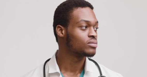 Retrato de estudio del médico afroamericano, girando cara a cámara y sonriendo ampliamente — Vídeos de Stock
