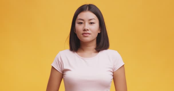 Pura felicidad. Joven alegre asiática dama mirando a la cámara y riendo, fondo naranja — Vídeos de Stock