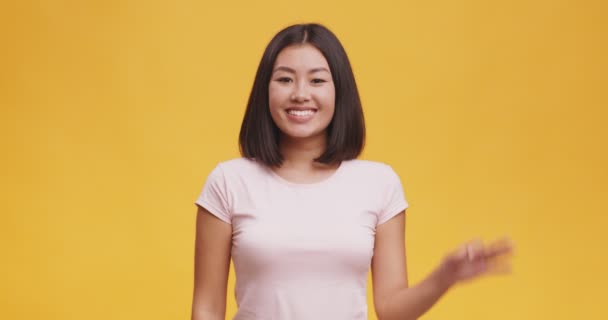 Alles ist in Ordnung. Positive junge asiatische Frau gestikuliert okay Zeichen und lächelt in die Kamera, orangefarbener Hintergrund — Stockvideo