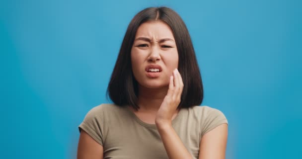 不快乐的年轻亚洲女人摸着脸颊，牙痛，突如其来的牙痛 — 图库视频影像