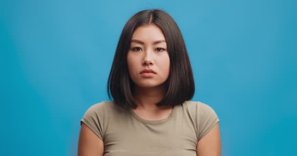 Young sick asian woman blowing nose into tissue, having seasonal cold or allergic reaction, blue studio background — Stock Video