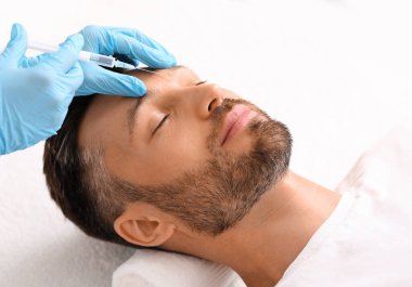 Kaş çizgilerine karşı insan kaşları arasındaki dolguyu enjekte eden kozmetolog.