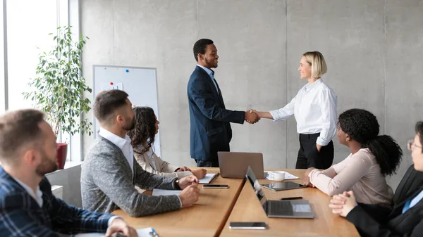 Empresário e empresária apertando as mãos após um acordo bem sucedido no escritório — Fotografia de Stock