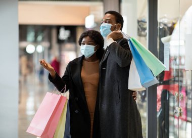 Mutlu Afro-Amerikan ailesi Kara Cuma 'dan kıyafet aldıktan sonra alışveriş merkezinde koruyucu maskeler takıyor.