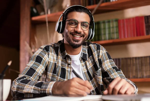 Portrait Of Happy Indian Student Sitting At Desk In Library