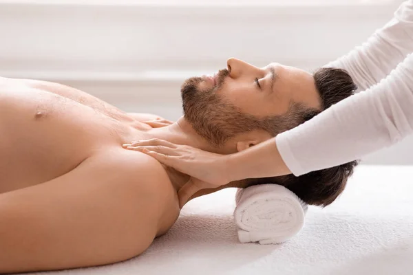Вид збоку радісного чоловіка, який отримує масаж тіла в спа-центрі — стокове фото