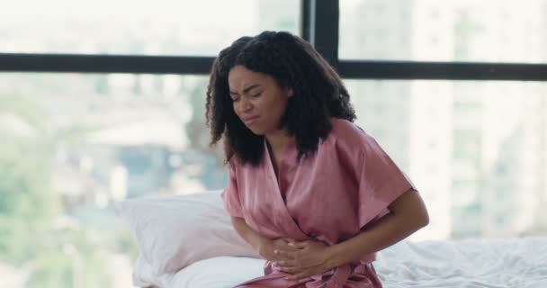 Mujer negra enferma que sufre de dolor de estómago sentada en la cama, sintiendo dolor abdominal o menstrual por la mañana — Vídeo de stock