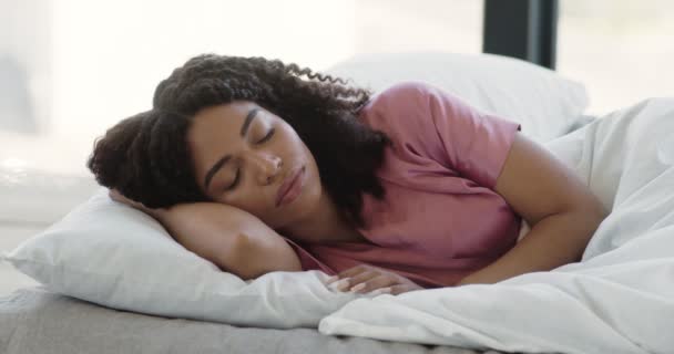 Calma jovem mulher negra dormindo bem em confortável e aconchegante cama fresca no travesseiro macio, desfrutando de um bom sono saudável — Vídeo de Stock