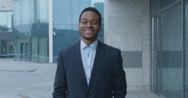 Başarılı Afro-Amerikan iş adamı takım elbiseli. Şirket binasının yanında yürüyor. Ağır çekim.