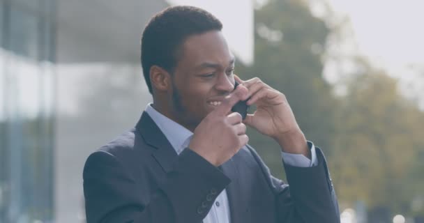 Negociações comerciais. Homem de negócios afro-americano preocupado falando no celular com colegas ou clientes ao ar livre — Vídeo de Stock