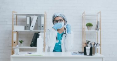 Doktor koruma maskesi takmanın önemiyle ilgili video kaydediyor ve covid-19 salgınını önlemek için elleri sterilize ediyor.