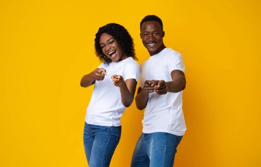 Neşeli genç Afrikalı Amerikalı çift kamerayı işaret ediyor.