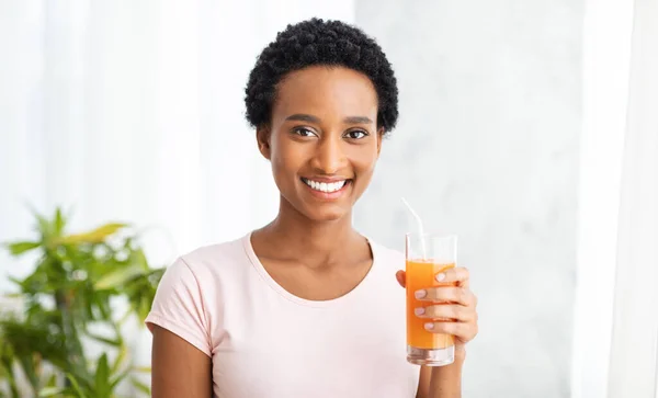 Note di alimentazione e concetto di disintossicazione. Donna nera sorridente con bicchiere di succo d'arancia fresco a casa, panorama — Foto Stock