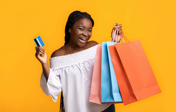 簡単ショッピング。喜び黒女性保持クレジットカードと明るいショッパーバッグ — ストック写真