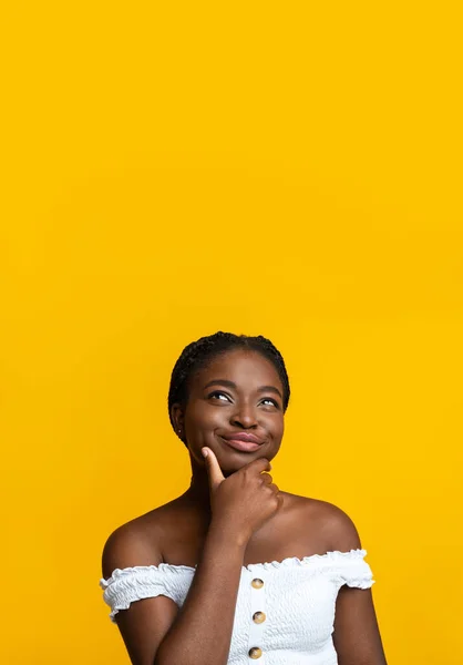 Застенчивая афроамериканская леди смотрит на пространство для копирования на желтом фоне — стоковое фото