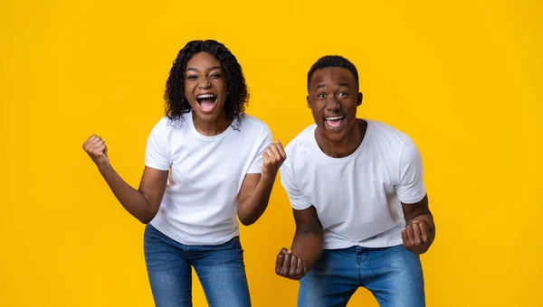 Feliz casal negro celebrando a vitória no amarelo — Fotografia de Stock