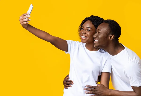 Alegre casal afro-americano levando selfie no smartphone, vista lateral — Fotografia de Stock