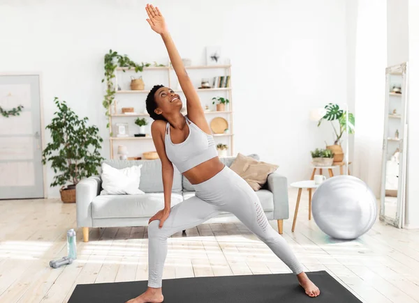 Ajuste mujer negra que estira su cuerpo en la estera del yoga durante su entrenamiento casero —  Fotos de Stock