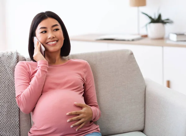 幸せな妊娠中のアジアの女性が自宅で電話で話している — ストック写真