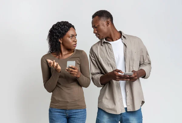 Black man with smartphone spying on his girlfriend — Stock Photo, Image