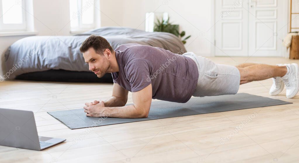 Sporty Guy Training At Computer Online Doing Plank Indoor, Panorama