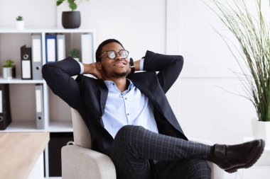 Genç Afrikalı iş adamı iş yerinde rahatlıyor.