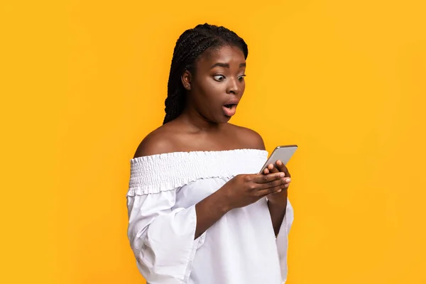 Nagy online értékesítés. Megdöbbent afro-amerikai nő néz Smartphone csodálkozva — Stock Fotó