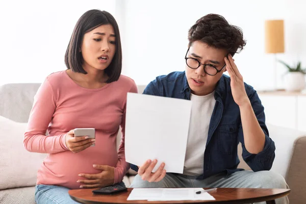 Nedstämd japansk par kämpar finansiella krisen tittar på räkningar inomhus — Stockfoto