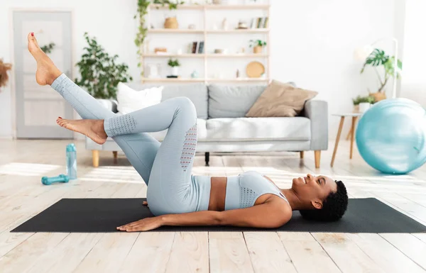 Entraînement sportif à domicile. Attrayant jeune femme couché sur tapis de yoga et cycing dans l'air, faire des exercices abdos dans le salon — Photo