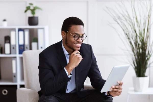 Alegre empresario negro sosteniendo tableta digital, interior de la oficina —  Fotos de Stock