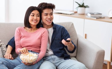 Çinli bir çift oturma odasında televizyon seyrediyor.