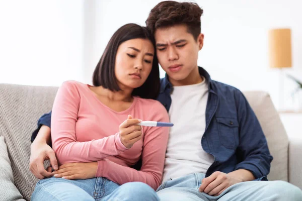 Frustrerat japanskt par som håller negativa graviditetstest hemma — Stockfoto