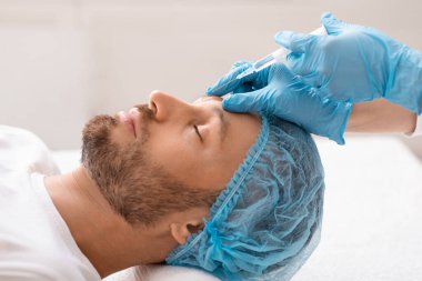 Orta yaşlı bir adam estetik kliniği ziyaret edip tedavi görüyor.