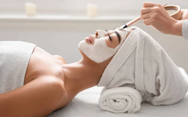 Kosmetikerin appliziert Detox-Maske auf junge asiatische Frauen Gesicht im Spa — Stockfoto