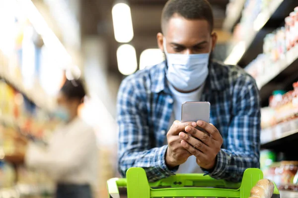 Black Man With Smartphone Shopping Food In Supermarket Wearing Mask — Stock Photo, Image