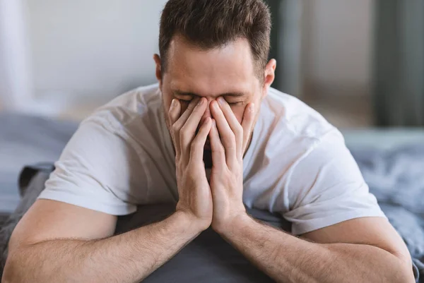 Guy esfregando os olhos acordando sonolento deitado na cama interior — Fotografia de Stock