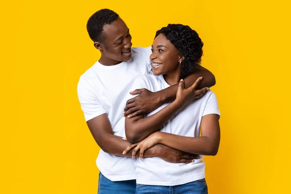 Happy black man and woman embracing, looking at each other