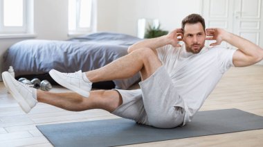 Evdeki jimnastik minderi üzerinde dizden dirseğe çıtırdatan adam.