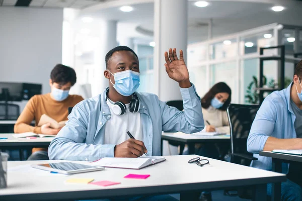 Noir étudiant levant la main, portant un masque médical — Photo