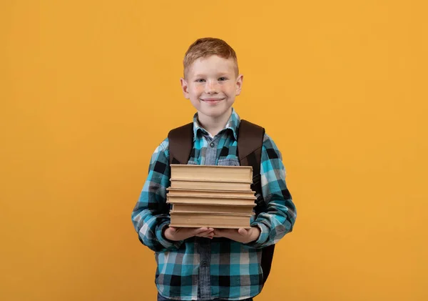 Estudante sorridente com mochila segurando montão de livros — Fotografia de Stock