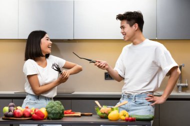 Çinli çift mutfak eskriminde aşçılık aletleriyle eğleniyor.