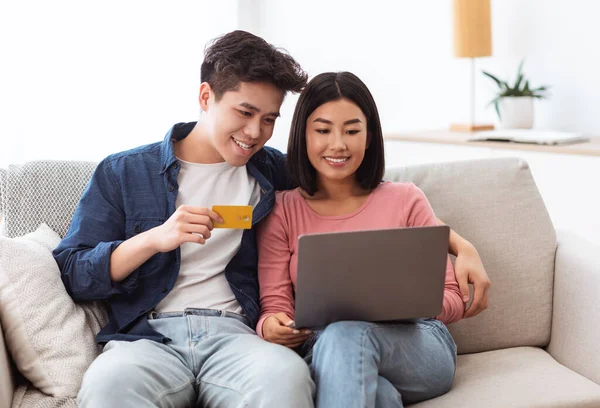 Casal chinês compras on-line com laptop e cartão de crédito interior — Fotografia de Stock