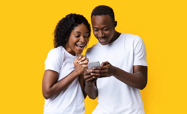 Emocionado casal preto olhando para a tela do telefone móvel — Fotografia de Stock