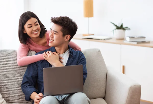 Casal asiático usando laptop navegação Internet sentado na sala de estar — Fotografia de Stock