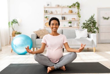 Nilüfer çiçekli yoga minderinde oturan, meditasyon yapan, nefes egzersizi yapan, sağlığıyla ilgilenen siyahi kadın.