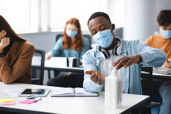Fekete tanuló antibakteriális fertőtlenítőt alkalmaz a kezén — Stock Fotó