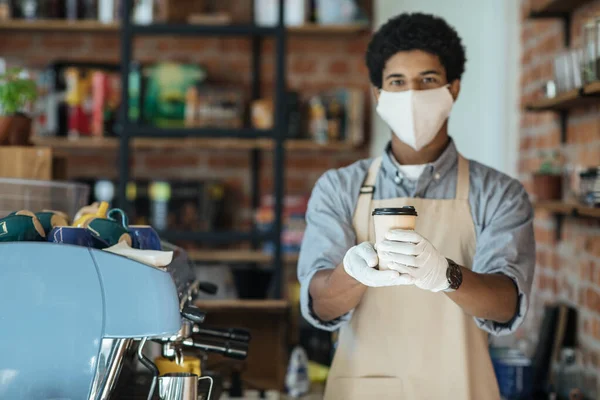 Garçom em máscara protetora médica serve café no restaurante durante a pandemia de coronavírus e novo normal — Fotografia de Stock