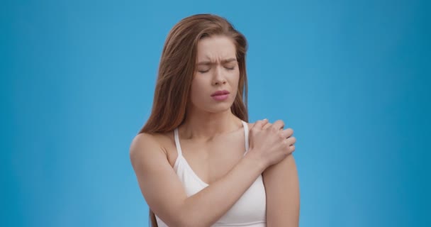 Douleur musculaire. Jeune femme souffrant de douleur à l'épaule, fond bleu studio, ralenti — Video