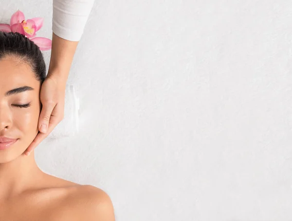 Beleza e Spa. Relaxado asiático senhora gozando facial massagem no wellness center — Fotografia de Stock